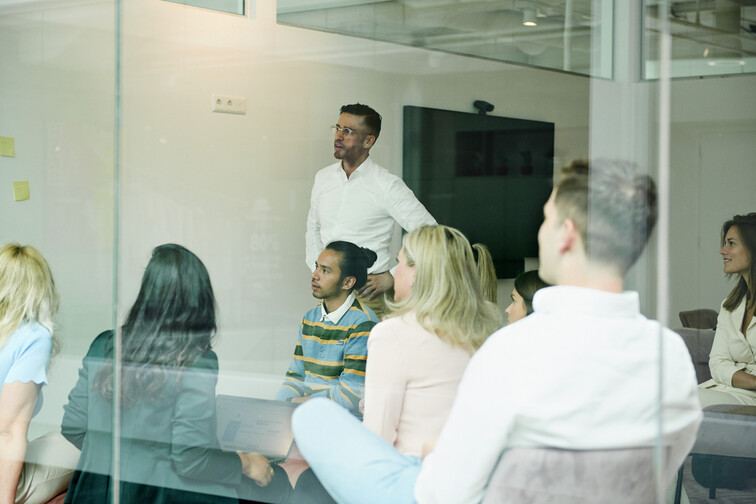 Colleagues sit in the office and discuss machine learning in front of the whiteboard.