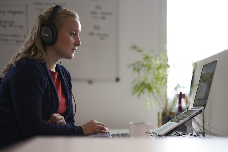 Woman working on computer with headset on