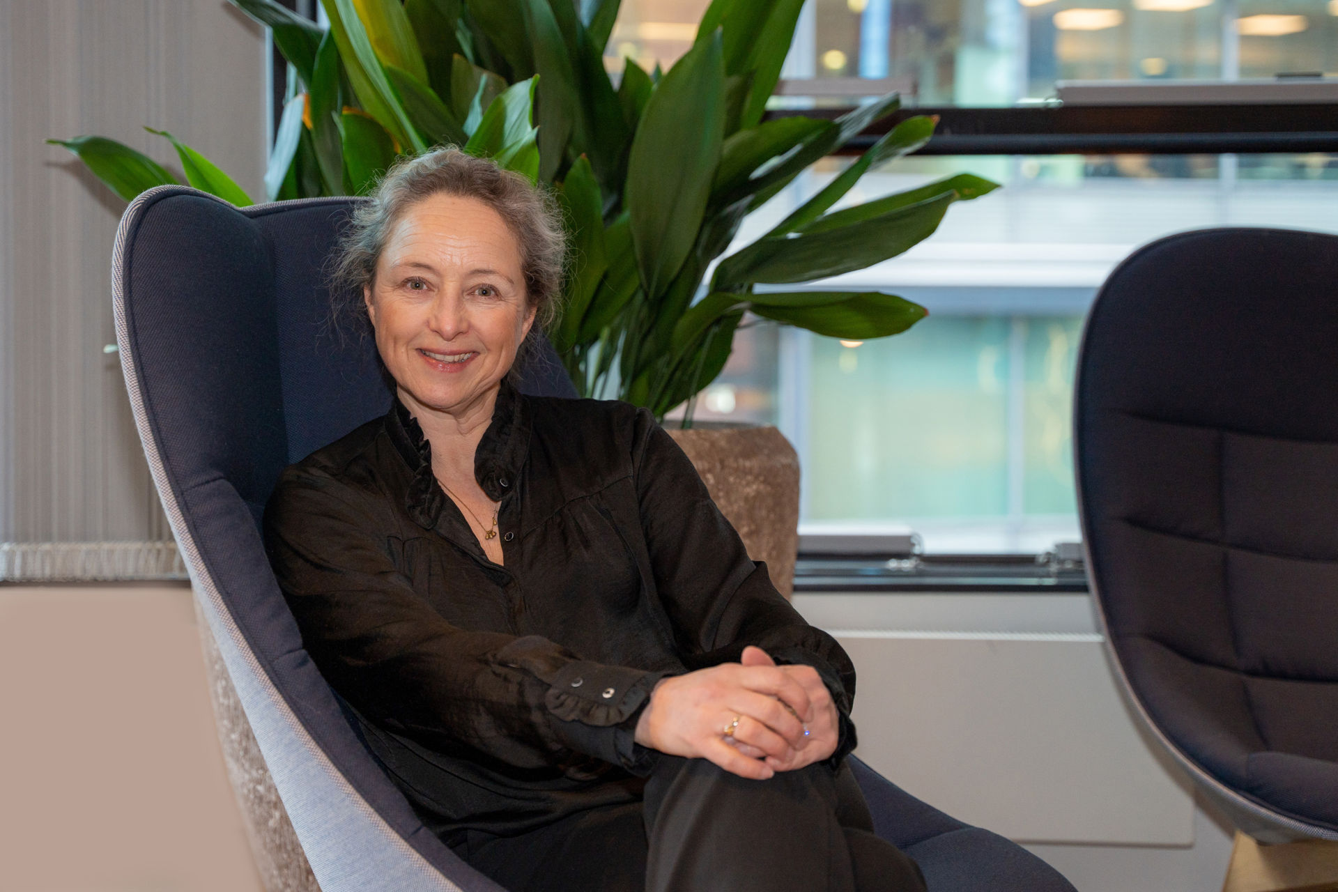 Yvette Hoogewerf sits comfortably in a chair with hands clasped on her lap.