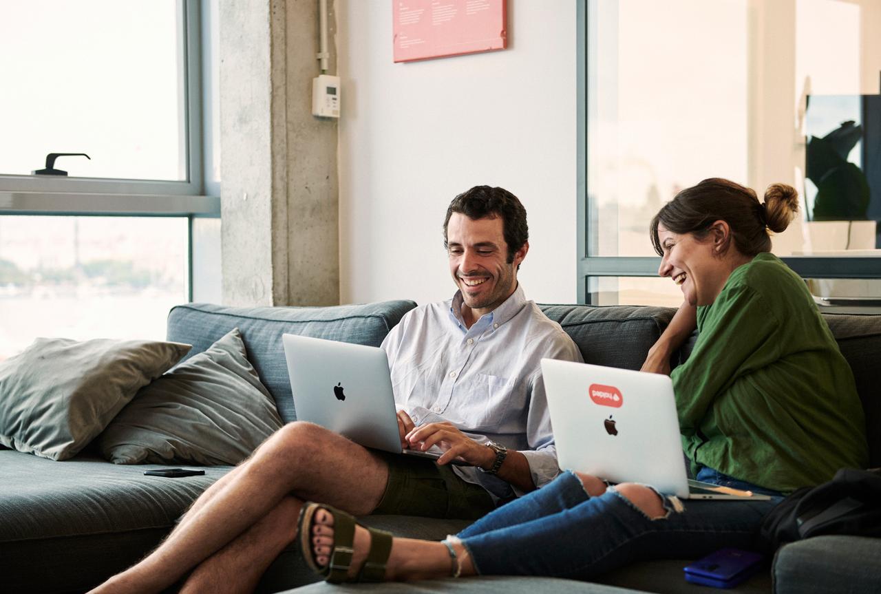 Woman and man sitting on coach working on laptops